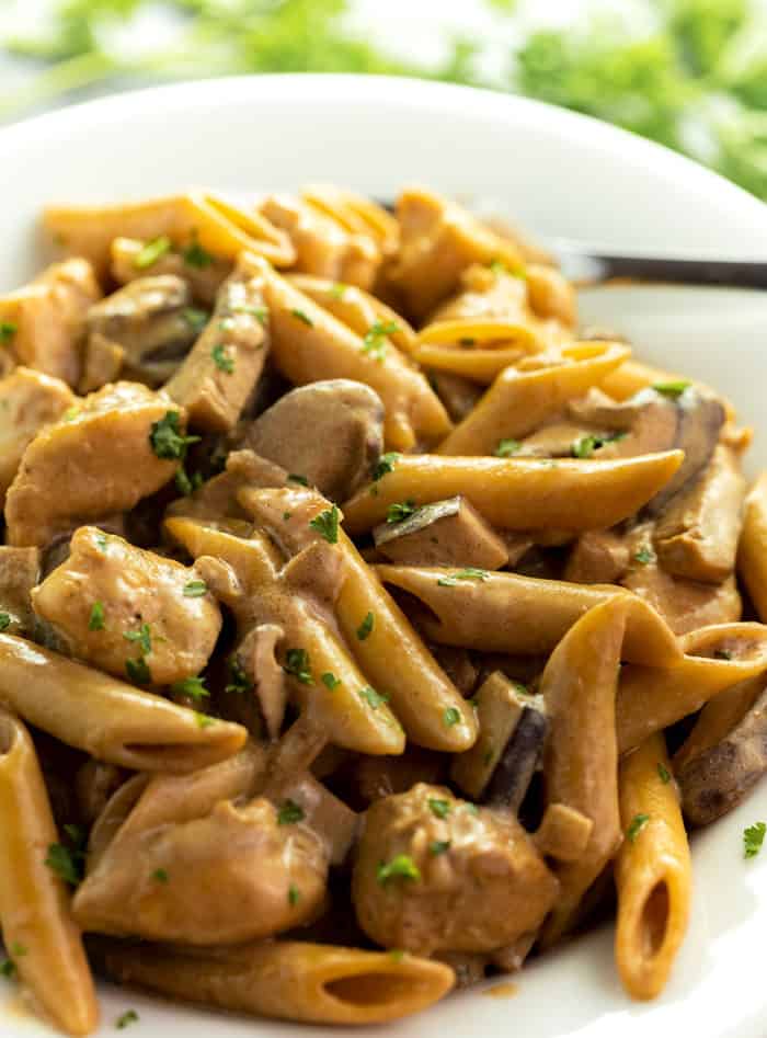 This Cheesecake Factory Copycat recipe for De Vinci Pasta is easy to make at home and is full of flavor! The savory pasta is surrounded by a creamy marsala wine sauce with swirls of caramelized onions and flavorful mushrooms! | The Cozy Cook | #Pasta #Marsala Close up image of De Vinci Pasta on a white plate with mushrooms and fresh parsley on top