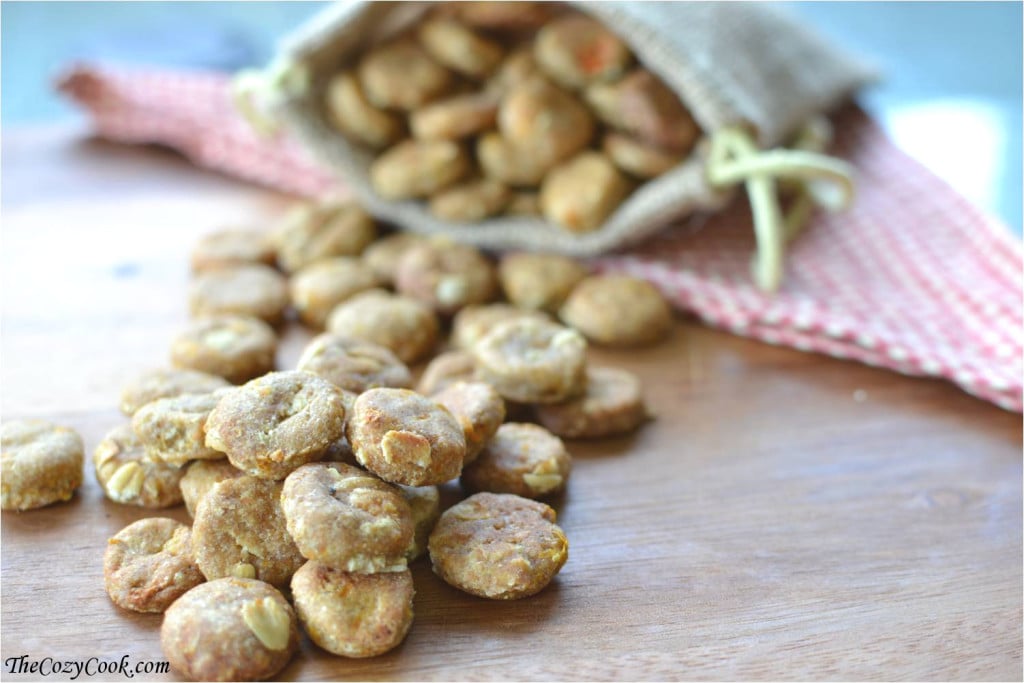 These homemade doggie snacks are packed with all-natural, wholesome ingredients that your favorite furry friend will LOVE! Round homemade dog treats spilling out of a pouch on a wooden surface.