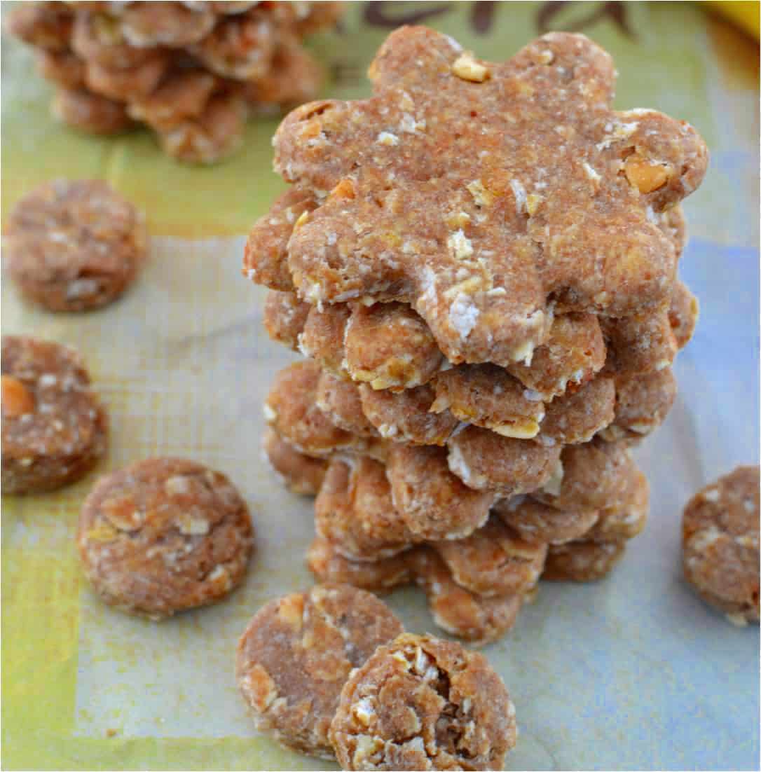 These homemade dog treats are filled with savory peanut butter and mashed banana- everything you need to keep your pup happy & energized! a stack of homemade dog treats in a flower shape with smaller round dog treats next to it.