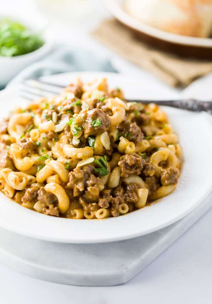This quick and easy instant pot hamburger helper puts dinner on the table in no time and tastes just like the classic hamburger helper recipe we know and love, minus the unknown ingredients! Homemade Hamburger Helper in a white bowl with a fork in the background.