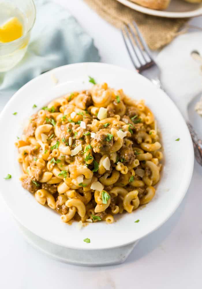 This quick and easy instant pot hamburger helper puts dinner on the table in no time and tastes just like the classic hamburger helper recipe we know and love, minus the unknown ingredients! Homemade Hamburger Helper in a white bowl with a glass of water next to it.