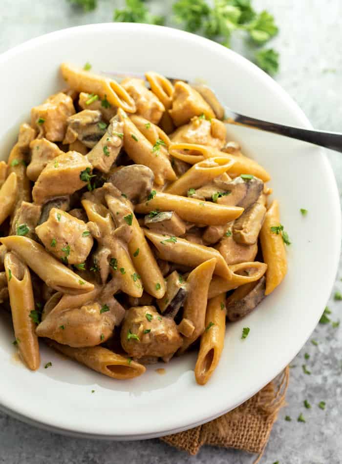 This Cheesecake Factory Copycat recipe for Pasta Da Vinci is easy to make at home and is full of flavor! The savory pasta is surrounded by a creamy marsala wine sauce with swirls of caramelized onions and flavorful mushrooms! | The Cozy Cook | #Pasta #Marsala Overhead shot of Pasta Da Vinci on a white plate with parsley in the back.