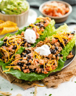 A plate with turkey taco lettuce wraps topped with sour cream.