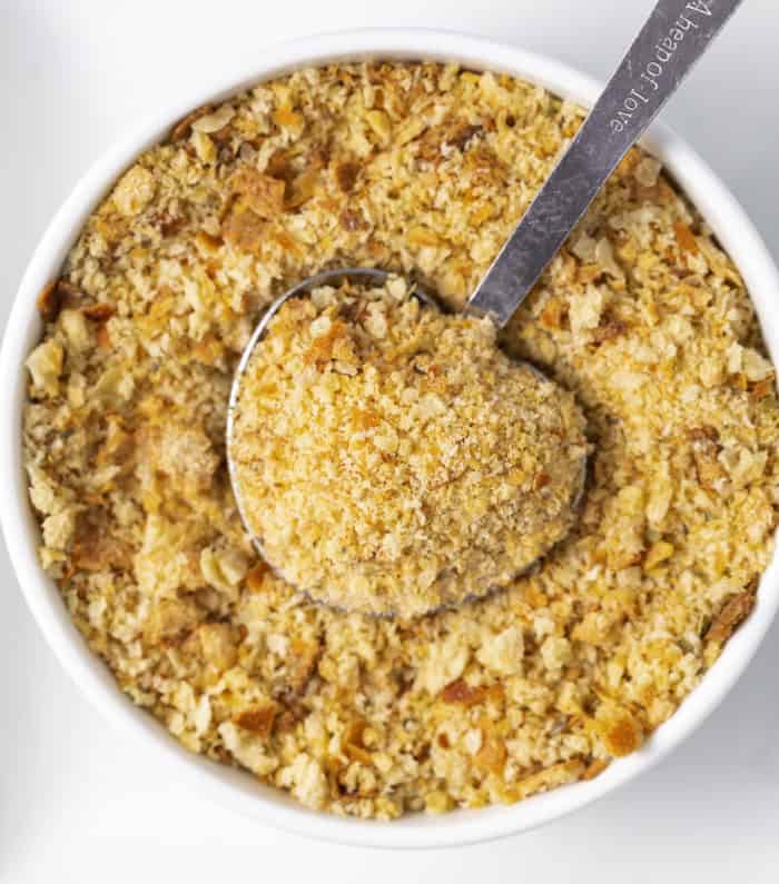 Learn how to make EASY homemade breadcrumbs! Store up to 3 months in the freezer and use for homemade meatballs, meatloaf, chicken, stuffing, casserole toppings, and more! #homemadebreadcrumbrecipe #easyrecipe #bread #breading #frying #panko A tablespoon in a white bowl full of homemade breadcrumbs.