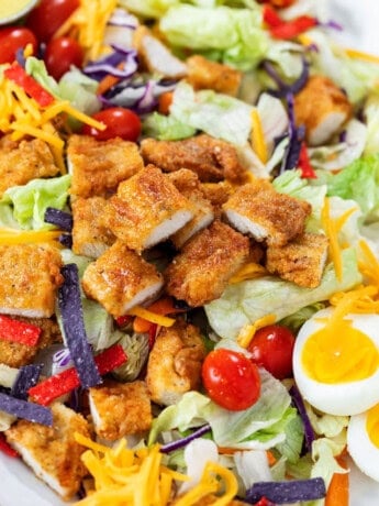 Crispy Chicken Salad with breaded chicken strips, lettuce, tomatoes, hard boiled eggs, cheese, and crispy tortilla crisps.