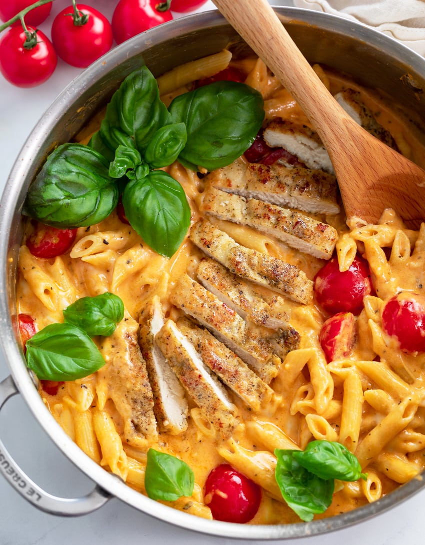 Creamy Caprese Pasta in a skillet with fresh cherry tomatoes and basil.