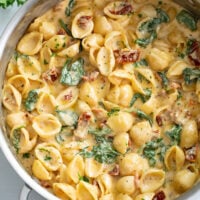 Tuscan Mac and Cheese in a skillet with a creamy cheese sauce with spinach and sundried tomatoes.