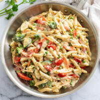 Pasta primavera in a skillet with a cream sauce and vegetables.