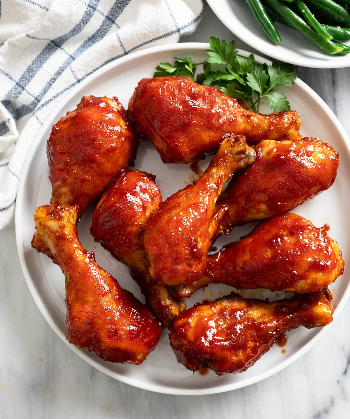 Overhead view of BBQ Chicken on a white plate with parsley on the side.