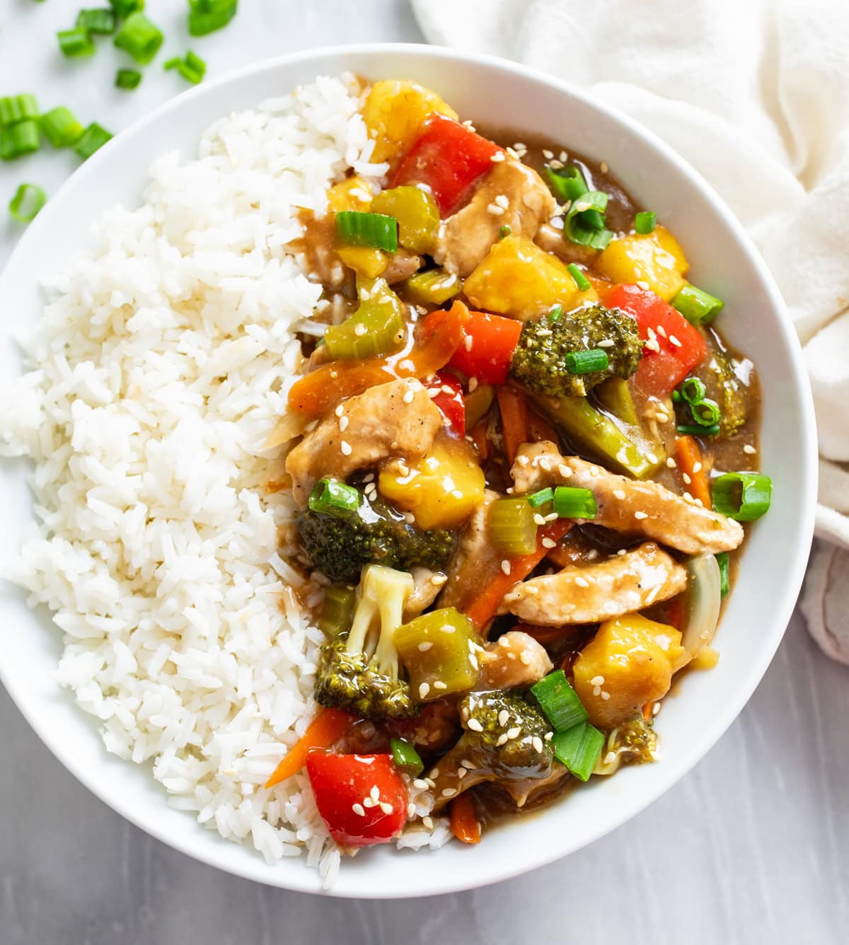 Pork Stir Fry with a brown sauce on a white plate with a bed of white rice.